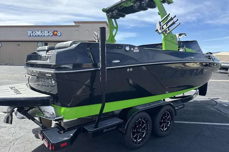Slide: The Image of 2022 Supra SA 450 boat in black and green on a trailer, parked outdoors. - 5