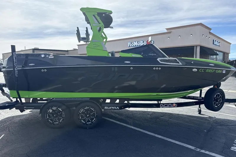 Slide: The Image of 2022 Supra SA 450 boat with green accents on a trailer in a parking lot. - 6
