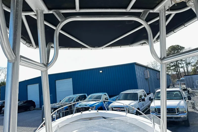 Slide: The Image of 2004 Angler Eagle Center Console boat with T-top, parked near blue warehouse and vehicles. - 4