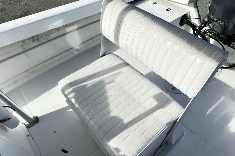 Slide: The Image of 2004 Angler Eagle Center Console boat seat with white upholstery and visible engine. - 6