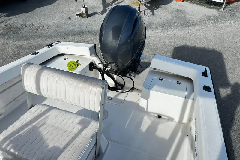 Slide: The Image of 2004 Angler Eagle Center Console boat interior with seating and motor, parked on gravel. - 9