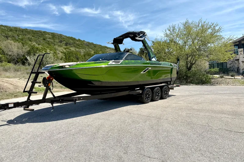 Slide: The Image of 2021 Centurion Ri245 boat in vibrant green on a trailer, parked outdoors. - 10