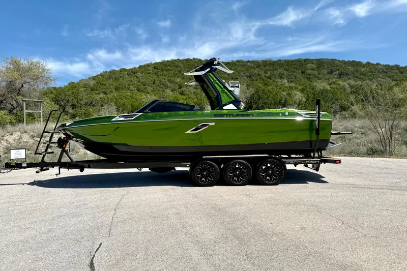 Slide: The Image of 2021 Centurion Ri245 boat on trailer, vibrant green, parked outdoors with scenic background. - 11