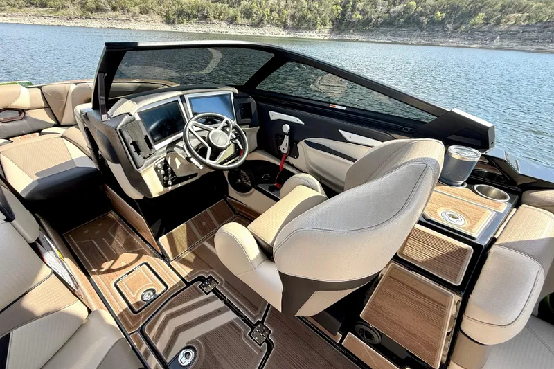 Slide: The Image of 2021 Centurion Ri245 boat interior with modern dashboard and luxurious seating by the water. - 25