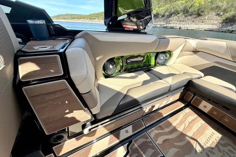 Slide: The Image of 2021 Centurion Ri245 boat interior with beige seating and wood accents, overlooking a scenic lake. - 27