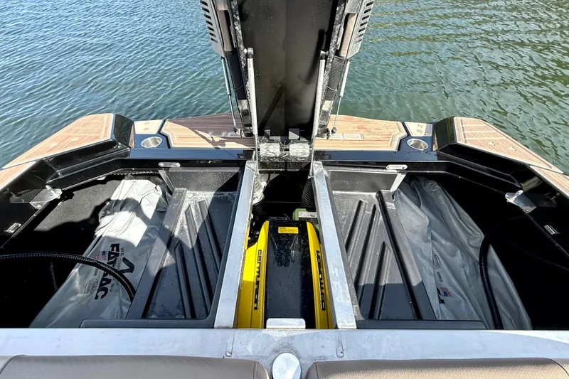 Slide: The Image of 2021 Centurion Ri245 boat storage compartments open, revealing interior details by the water. - 33