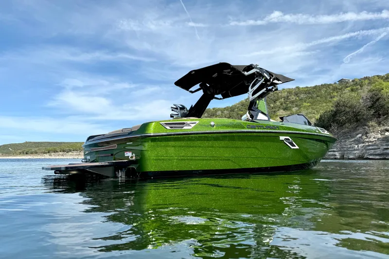 Slide: The Image of 2021 Centurion Ri245 boat in vibrant green on a serene lake with clear skies. - 4