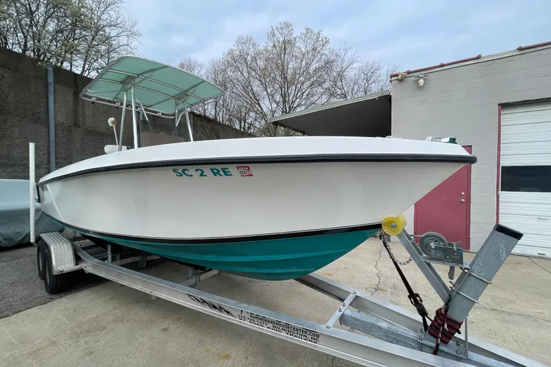 Slide: The Image of 1999 Contender 23 CC boat on trailer, parked outside a garage. - 3