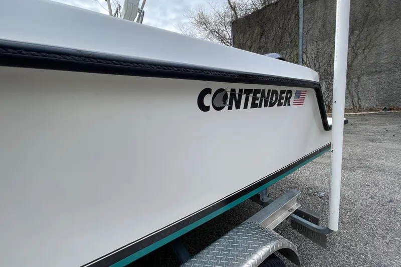 Slide: The Image of 1999 Contender 23 CC boat on trailer, side view with logo visible. - 7
