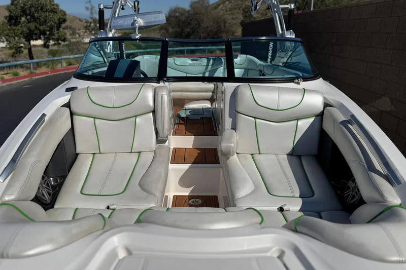 Slide: The Image of 2013 MasterCraft XStar boat interior with white and green seating, wood accents, and open cockpit. - 13