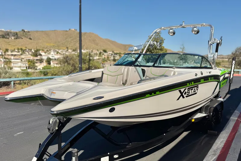 Slide: The Image of 2013 MasterCraft XStar boat on trailer, parked with scenic background. - 4