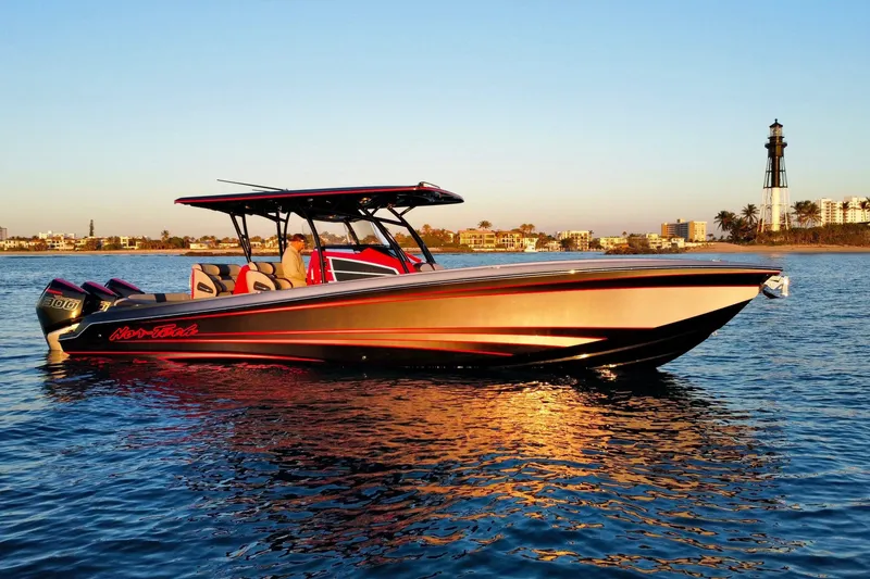 Slide: The Image of 2024 Nor-Tech 340 Sport Center Console boat on water at sunset near a lighthouse. - 2
