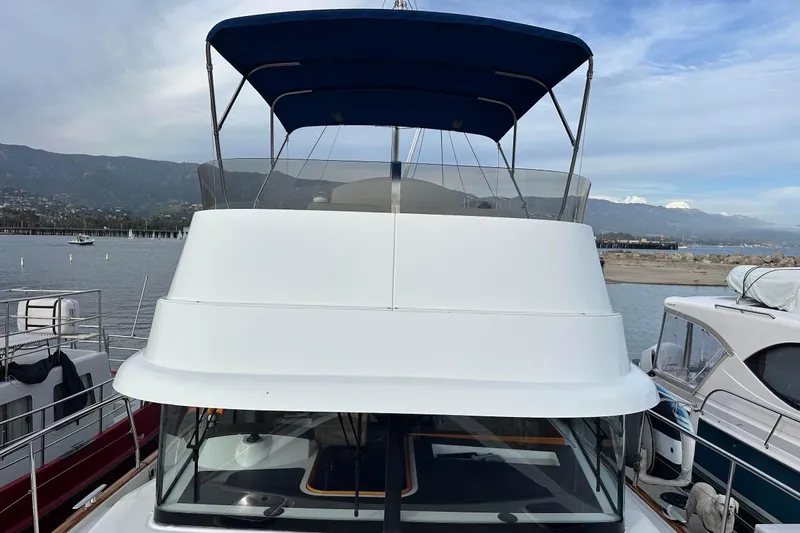 Slide: The Image of 2015 Beneteau Swift Trawler 44 docked, featuring a blue canopy and scenic coastal backdrop. - 10