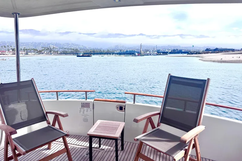 Slide: The Image of Beneteau Swift Trawler 44 deck view with chairs overlooking serene coastal waters, 2015 model. - 12