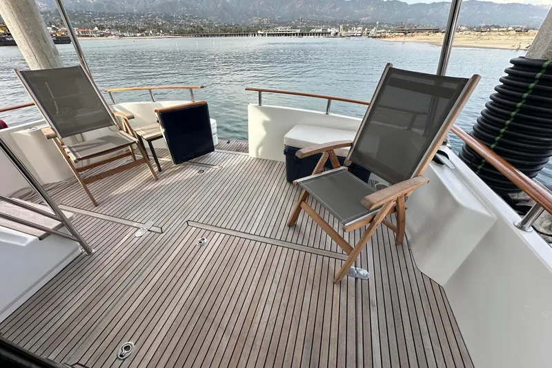 Slide: The Image of Deck of 2015 Beneteau Swift Trawler 44 with chairs, overlooking serene waters and distant mountains. - 13