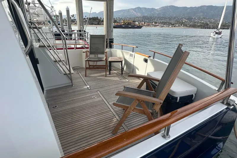 Slide: The Image of 2015 Beneteau Swift Trawler 44 deck with chairs, overlooking serene waters and distant mountains. - 14