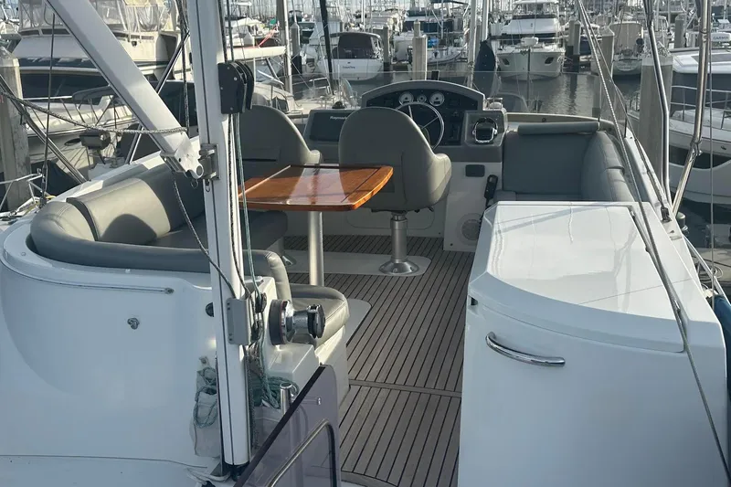 Slide: The Image of 2015 Beneteau Swift Trawler 44 interior with helm, seating, and wooden table in marina setting. - 22
