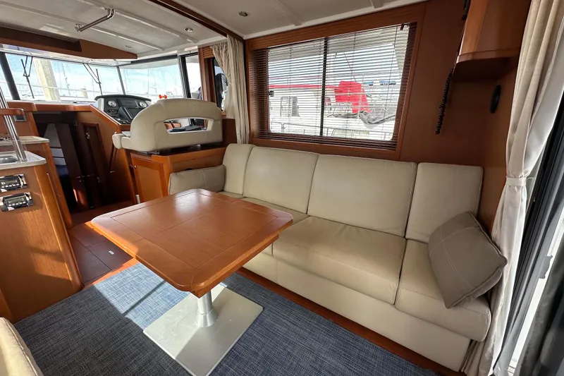 Slide: The Image of Interior of 2015 Beneteau Swift Trawler 44 with beige sofa and wooden table. - 32