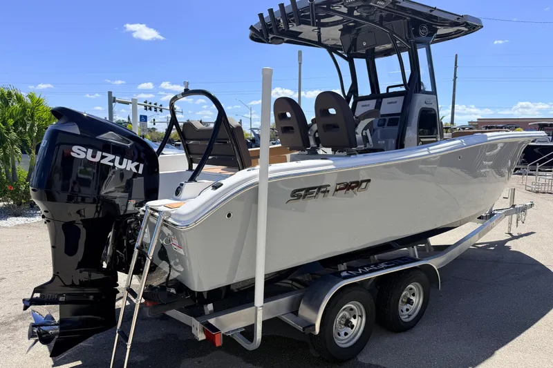 Slide: The Image of 2026 Sea Pro 245FLXR Sandbar boat with Suzuki engine on a trailer, under clear blue sky. - 6