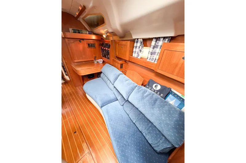 Slide: The Image of Interior of 2002 Hunter 380 sailboat with blue seating and wooden cabinetry. - 15