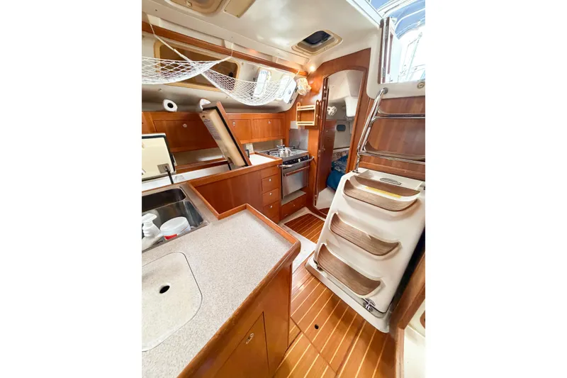Slide: The Image of Interior of a 2002 Hunter 380 sailboat featuring a compact kitchen and wooden cabinetry. - 18