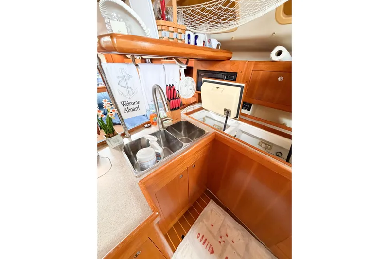 Slide: The Image of 2002 Hunter 380 yacht kitchen with sink, wooden cabinetry, and nautical decor. - 26