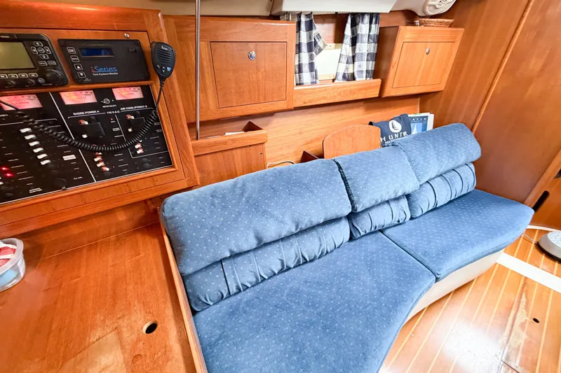 Slide: The Image of Interior of 2002 Hunter 380 yacht with blue cushioned seating and wooden cabinetry. - 39