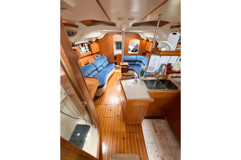Slide: The Image of Interior of 2002 Hunter 380 sailboat with wooden flooring and blue seating. - 56