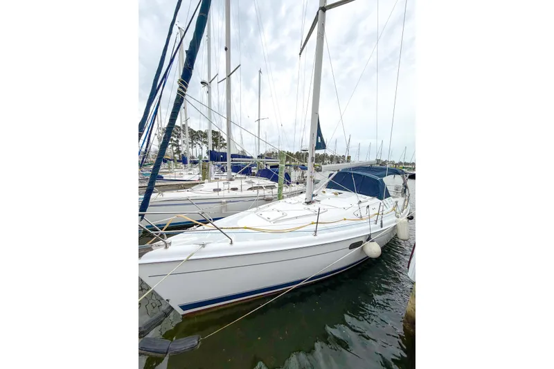 Slide: The Image of 2002 Hunter 380 sailboat docked in a marina, featuring white hull and blue accents. - 77