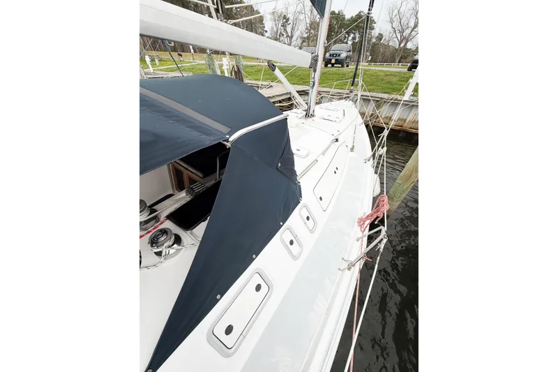 Slide: The Image of 2002 Hunter 380 sailboat docked, featuring sleek white deck and navy canopy. - 9