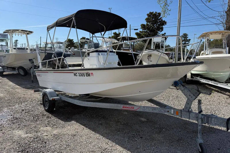 Slide: The Image of 2015 Boston Whaler 170 Montauk boat on trailer, parked outdoors under clear sky. - 11