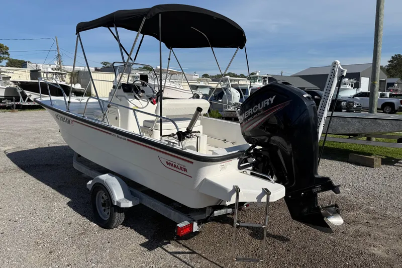 Slide: The Image of 2015 Boston Whaler 170 Montauk boat with Mercury engine on trailer, parked outdoors. - 4