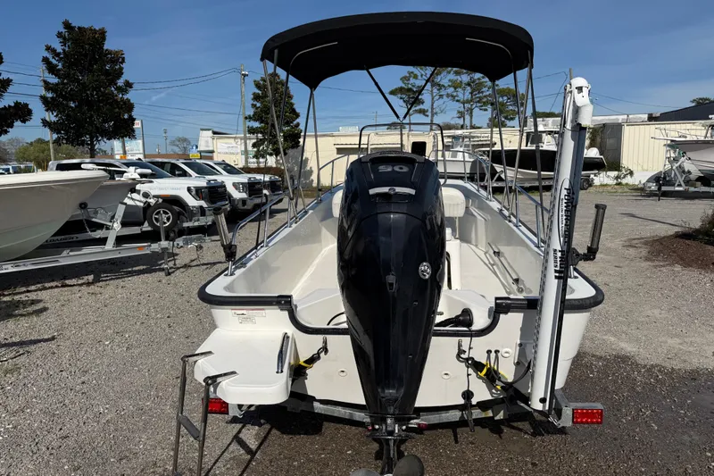 Slide: The Image of 2015 Boston Whaler 170 Montauk boat with outboard motor and canopy, parked on gravel. - 6