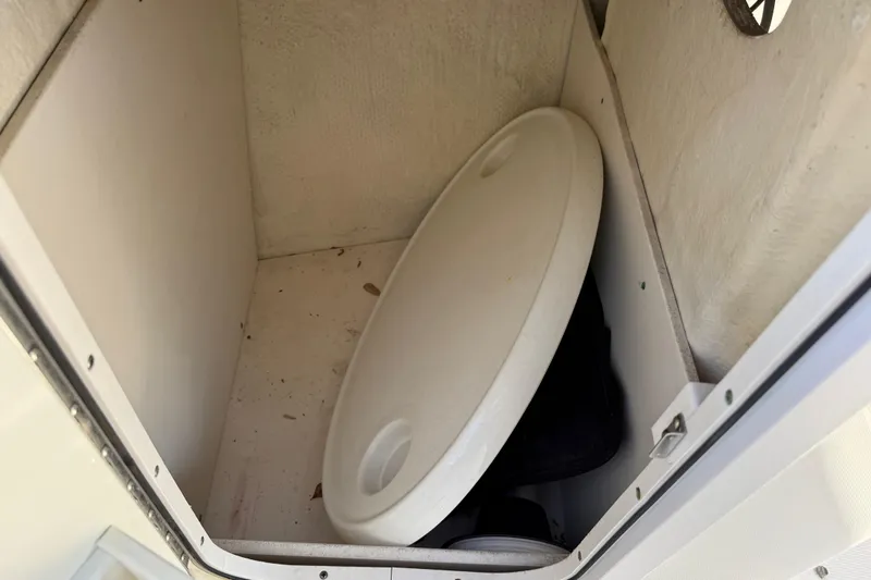 Slide: The Image of Storage compartment in a 2015 Robalo R227 Dual Console boat, featuring a white lid. - 26