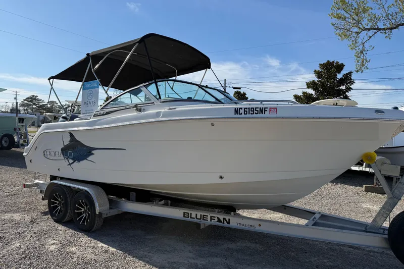 Slide: The Image of 2015 Robalo R227 Dual Console boat on trailer, for sale, under clear blue sky. - 8