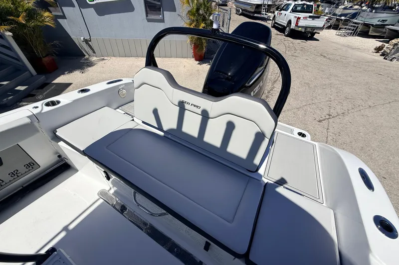 Slide: The Image of 2026 Sea Pro 225FLX Sandbar boat interior with seating and motor, parked outdoors. - 24
