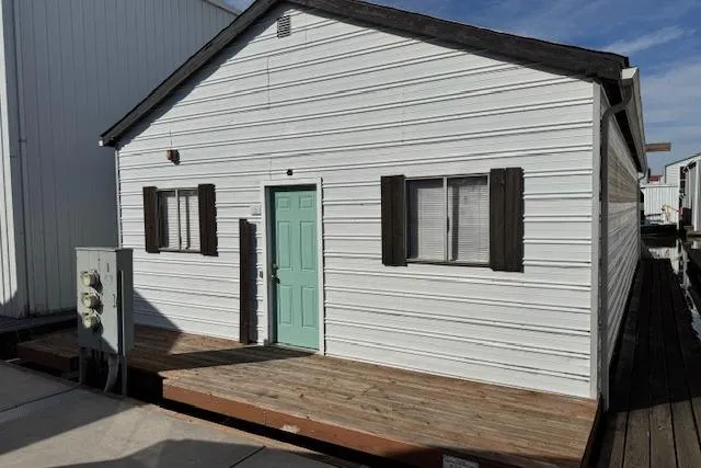 The Image of 1960 custom boathouse with white siding, teal door, and wooden deck. - 1