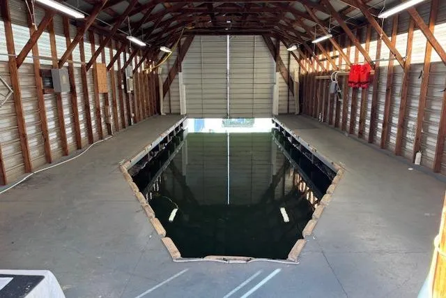 Slide: The Image of 1960 custom boathouse interior with water dock, wooden beams, and open garage door. - 4