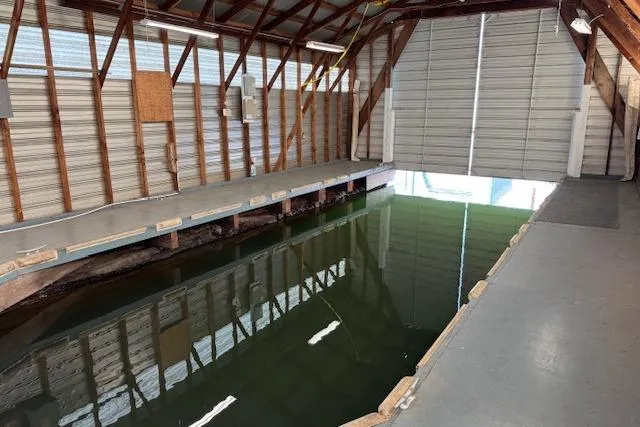 Slide: The Image of 1960 custom boathouse interior with water channel and open garage door. - 5