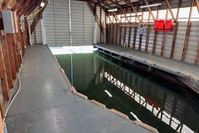Slide: The Image of 1960 custom boathouse interior with dock, water channel, and life jackets on wooden walls. - 6