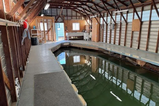 Slide: The Image of 1960 custom boathouse interior with wooden beams, dock, and water channel. - 9