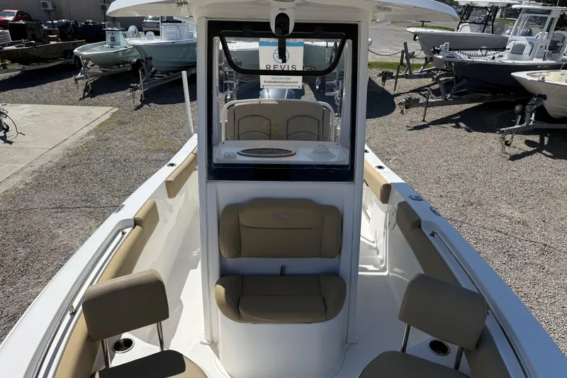 Slide: The Image of 2018 Sea Hunt Ultra 235 SE boat interior with seating and console, parked on gravel. - 16