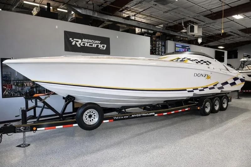 The Image of 1998 Donzi 38 ZX speedboat on trailer in showroom, featuring sleek design and racing graphics. - 1