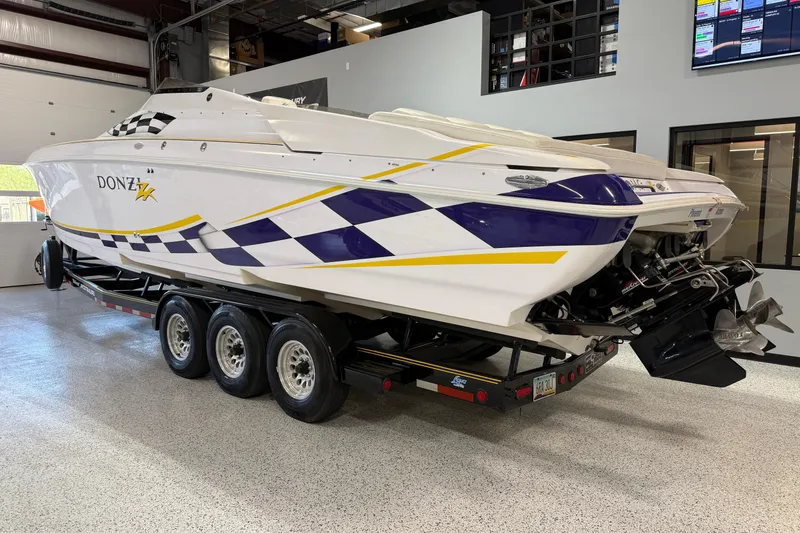 Slide: The Image of 1998 Donzi 38 ZX speedboat with vibrant graphics on a triple-axle trailer in a showroom. - 3