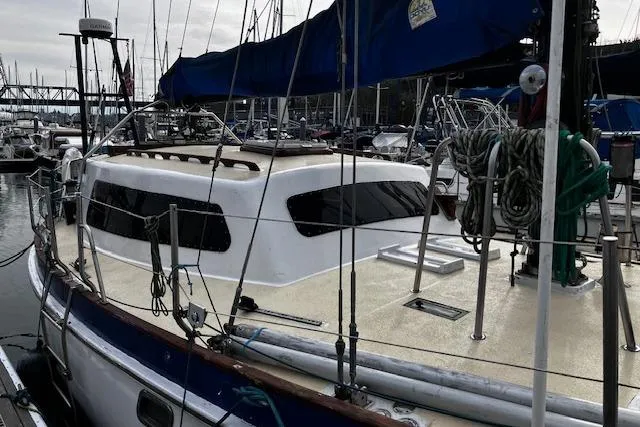 Slide: The Image of 1984 Swanson 42' Cutter sailboat docked in a marina, featuring a sleek cabin design. - 2