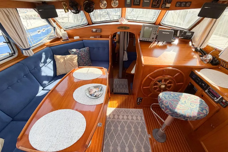 Slide: The Image of Interior of a 1986 Nauticat 40 sailboat with wooden helm and cozy seating area. - 32