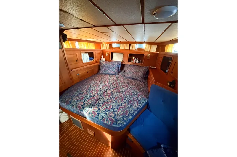 Slide: The Image of Cozy cabin interior of 1986 Nauticat 40 sailboat with patterned bedding and wooden furnishings. - 48