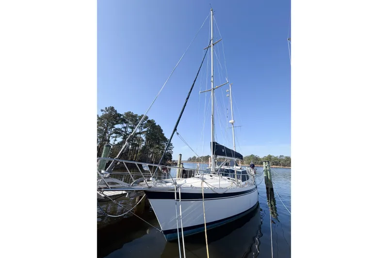 Slide: The Image of 1986 Nauticat 40 sailboat docked on a sunny day, surrounded by trees and calm water. - 6