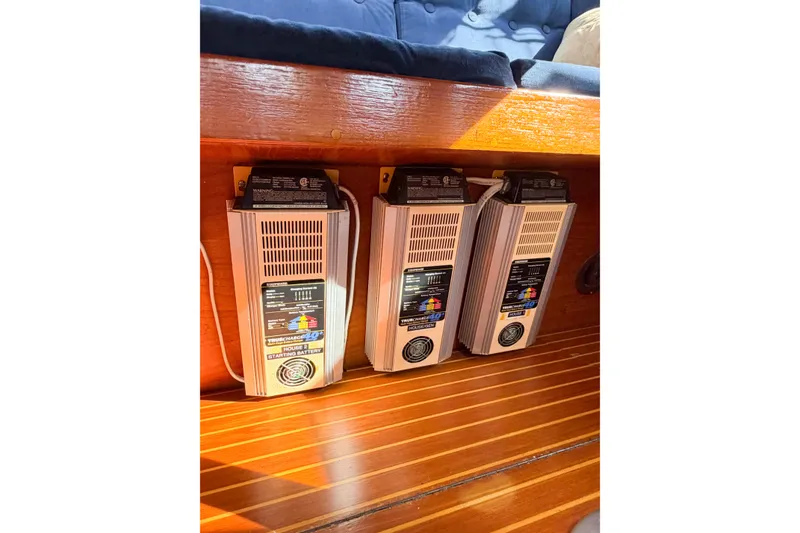 Slide: The Image of Battery chargers installed on a 1986 Nauticat 40 sailboat, featuring wooden interior paneling. - 60