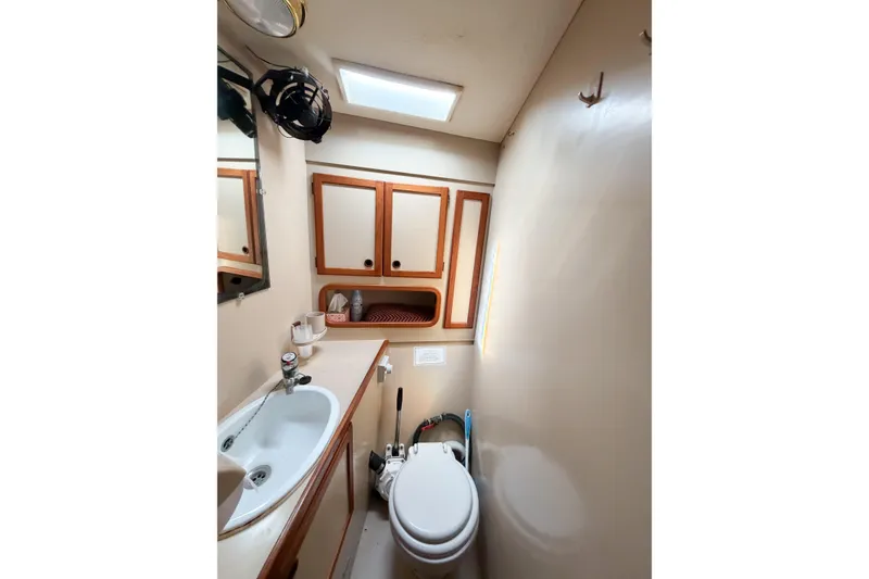 Slide: The Image of Compact bathroom in a 1986 Nauticat 40 sailboat with sink, toilet, and storage cabinets. - 68